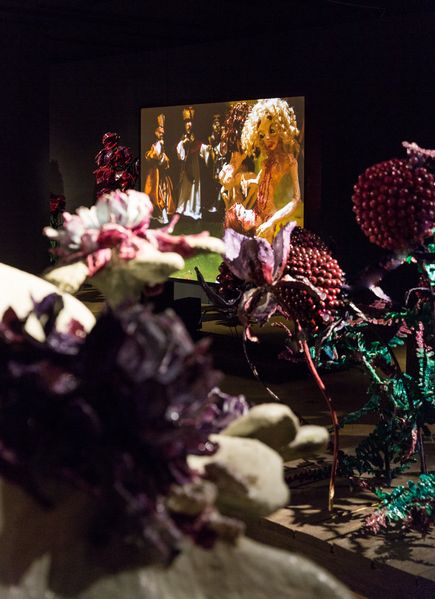 Düstere, begehbare Installation aus uberdimensionalen Blumenskulpturen und Videoprojektionen