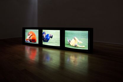 Video installation of three monitors lined up side by side on the floor, all three showing different scenes of falling soccer players in close-up. Paul Pfeiffer, Sammlung Goetz Munich