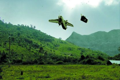 Video Still, das eine grüne, bergige Landschaft Vietnams mit blauem Himmel zeigt, von dem ein getroffenes Militärflugzeug stürzt. David Claerbout, Sammlung Goetz München