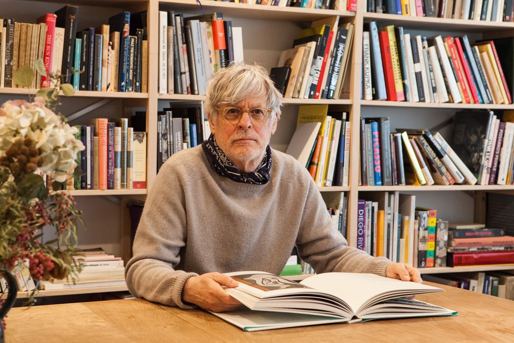 Der Künstler Rodney Graham sitzt in seiner Bibliothek und blättert in einem Buch über Picasso, Sammlung Goetz München
