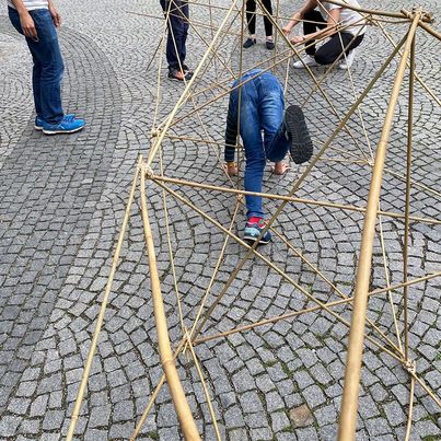 Kinder klettern durch eine räumliche Struktur aus dünnen Stäben 