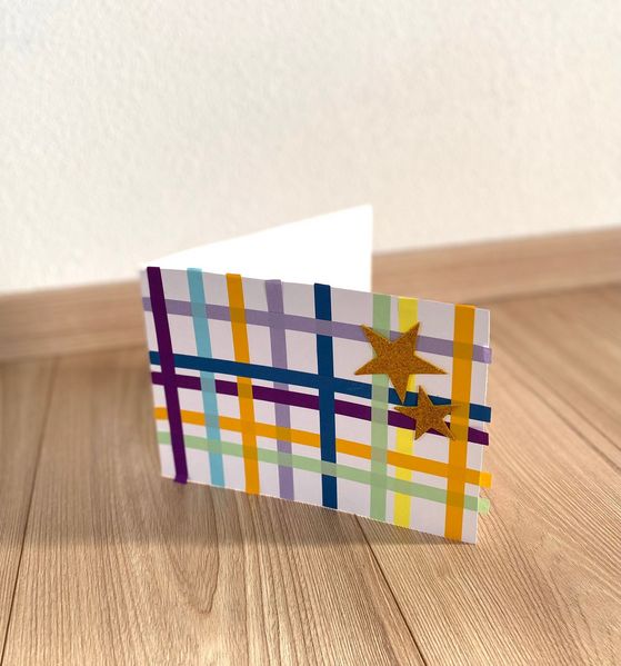 Klappkarte mit bunten Papierstreifen und goldenen Sternen