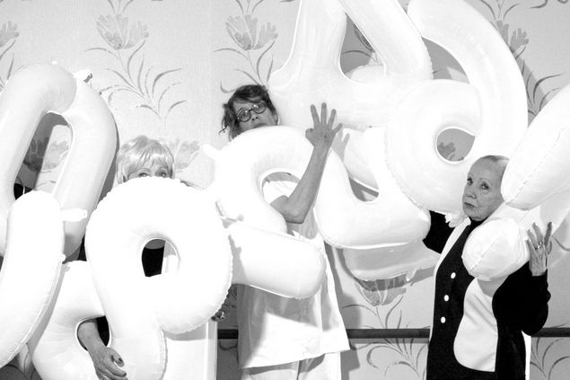 Black and white photograph of four women holding number balloons