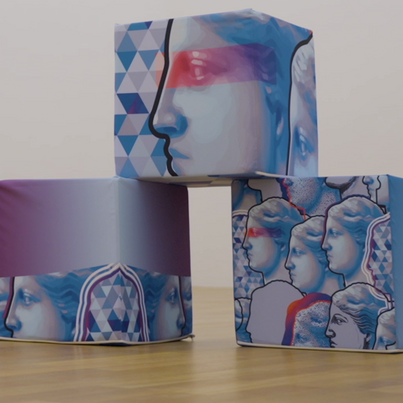 In einem leeren Raum stehen drei Würfel mit dem Logo vom Bayerischen Staatsministerium für Wissenschaft und Kunst