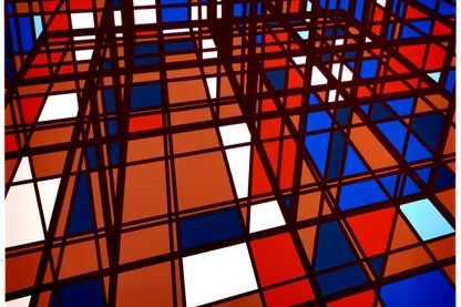 Abstrakte, minimalistische Malerei bestehend aus einem schwarzen Gitter, die der Malerei Räumlichkeit verschafft. Die darin befindlichen Vierecke sind in den Farben Rot, Weiß, Dunkel- und hellblau sowie Orange gehalten. Sarah Morris, Sammlung Goetz München 