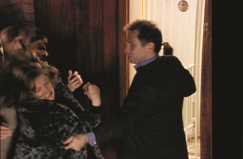This film still shows a man grabbing a woman by the arm, trying to slap her. The woman tries to protect herself by turning her head away.