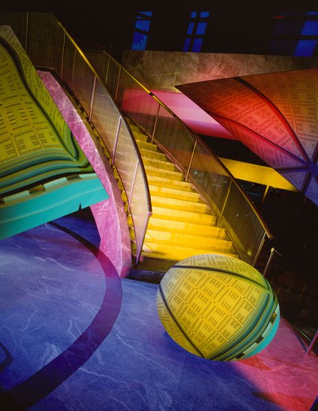 Color photograph of an abstract geometric composition with a staircase and geometrical shapes (triangles, sphere), Barbara Kasten, Sammlung Goetz, Munich.