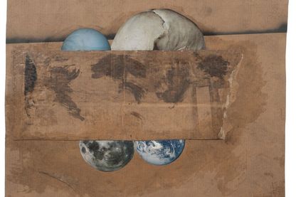 Four spherical objects including a half skull partially covered by a rectangular brown cardboard on a brown cardboard background
