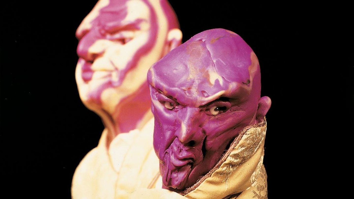 This photograph consists of a close-up of two male head sculptures. They have no hair, but an expressive facial expression. They are also dressed with high-quality fabrics. 