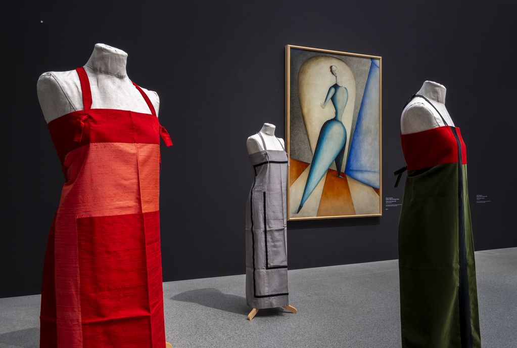 Andrea Zittel aprons on mannequins, behind them the painting "Dancer" by Oskar Schlemmer