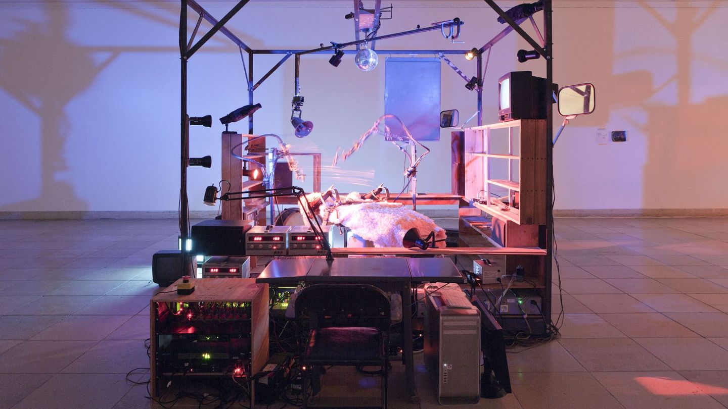 Rauminstallative Arbeit, die eine Maschine enthält, bestehend aus einem Zahnarztstuhl, Schwarzweißfernsehapparate, Robotertechnik, Pneumatik, einer Gitarre sowie einem Computer. Ein beweglicher Megaphonlautsprecher umgibt einen elektrischen Zahnarztstuhl. Der Stuhl ist mit einem rosafarbenen Kunstfell mit Lederriemen und Stacheln überzogen. In der Installation befinden sich zwei Roboterarme, die schweben und sich bewegen - mal wie in einem Ballett, mal greifen sie den unsichtbaren Gefangenen auf dem Stuhl mit pneumatischen Kolben an. Eine Discokugel dreht sich über dem Mechanismus und reflektiert eine Reihe von farbigen Lichtern, während eine von einem Roboterstab angeschlagene Gitarre klagt und eine Wand aus alten Fernsehern sich an- und ausschaltet und ein unheimliches Leuchten erzeugt. Janet Cardiff/George Bures Miller, Sammlung Goetz München