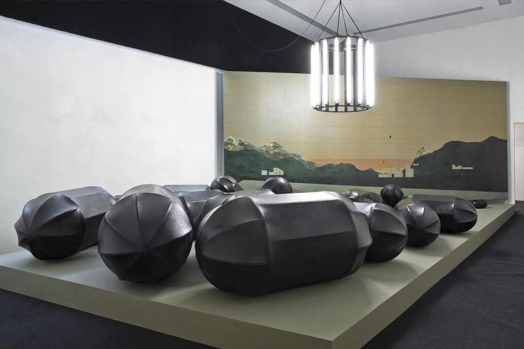 Installation view of the artwork "Dirty Tree Black Pills", consisting of 30 black bomb sculptures, a chandelier and a painted canvas. Thomas Zipp, Sammlung Goetz Munich