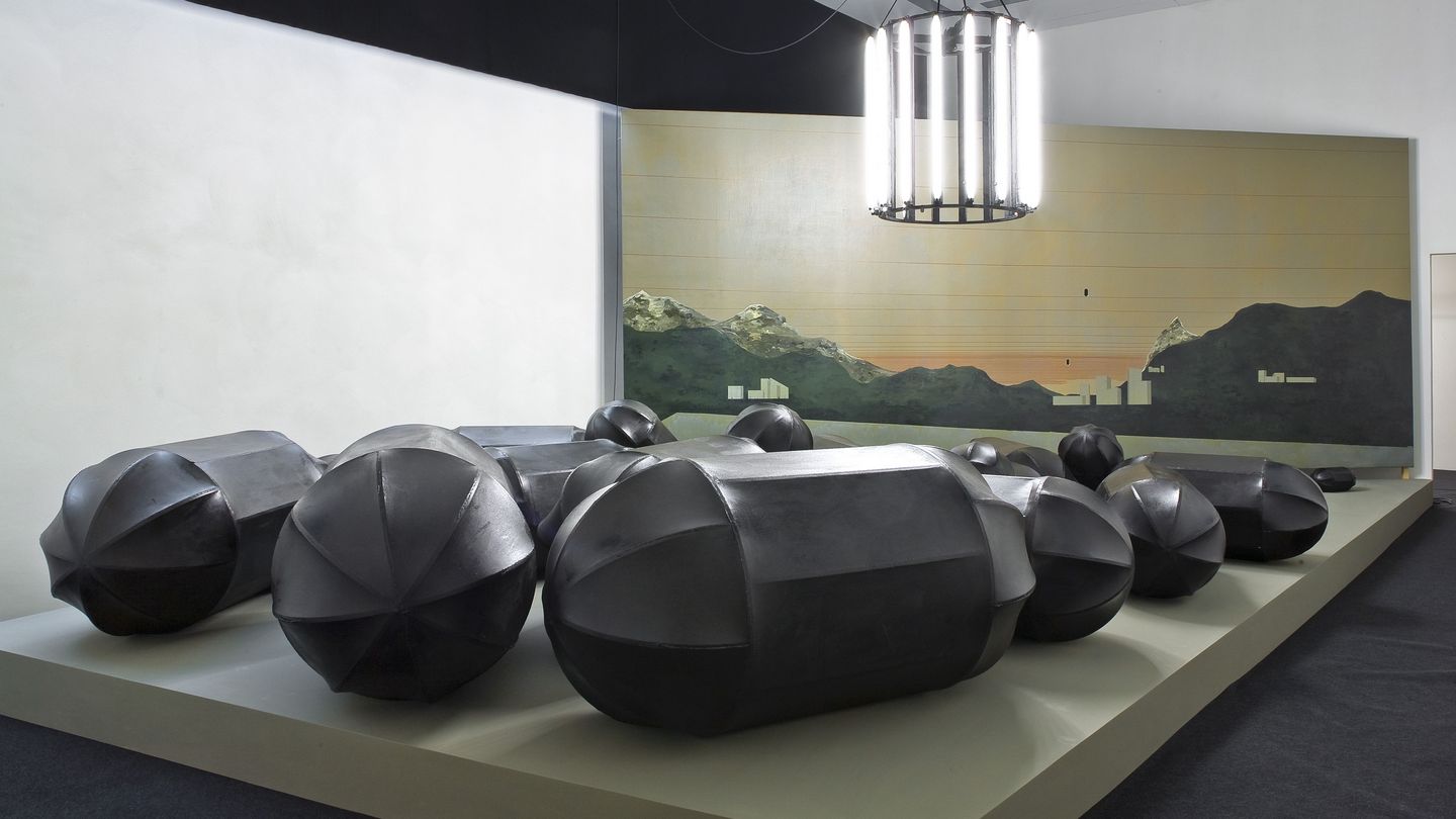Installationsansicht der Arbeit "Dirty Tree Black Pills", bestehend aus 30 schwarzen Bombenskulpturen, einem Leuchter und einer bemalten Leinwand. Thomas Zipp, Sammlung Goetz München
